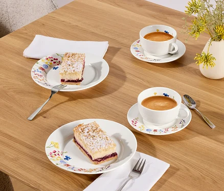 Deux parts de gâteau et deux tasses de café sur une table en bois.