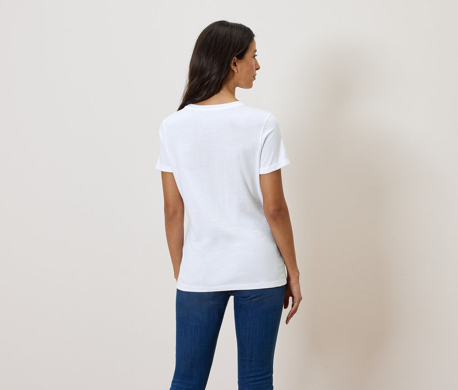 Vue de dos d'une femme aux cheveux foncés portant un t-shirt blanc et un jean bleu.