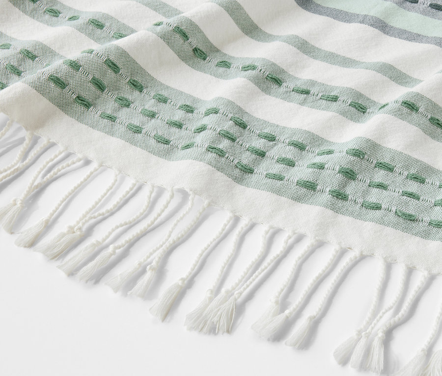 Vue détaillée d'un plaid à franges blanches et rayures vertes.