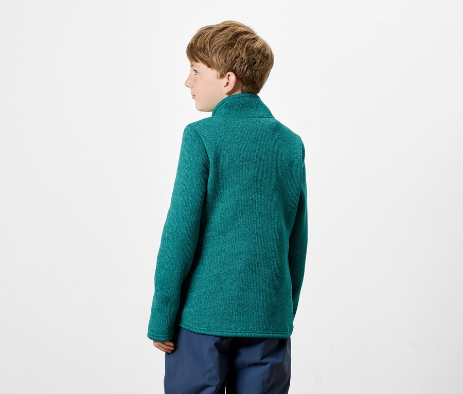 Garçon portant un pull vert et un pantalon bleu.