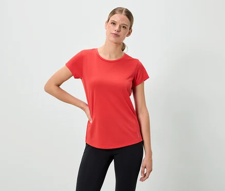 Une femme pose dans un t-shirt rouge et un legging noir.