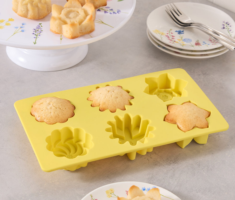 Moules à gâteaux en forme de fleurs sur assiettes et dans un moule en silicone jaune.