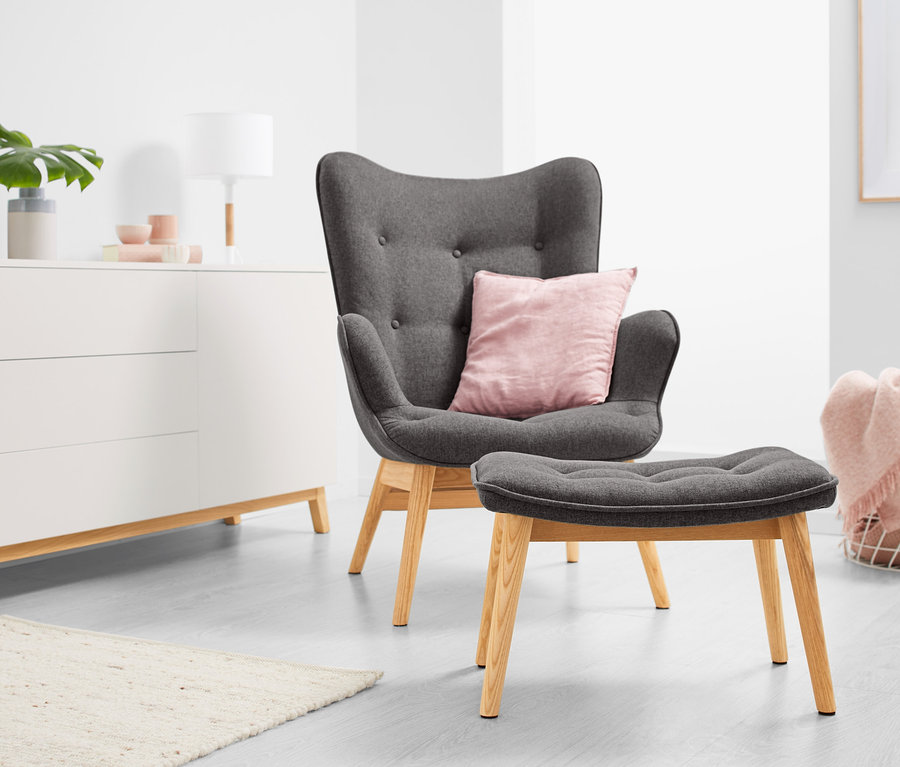 Fauteuil individuel gris foncé avec repose-pieds dans un salon.