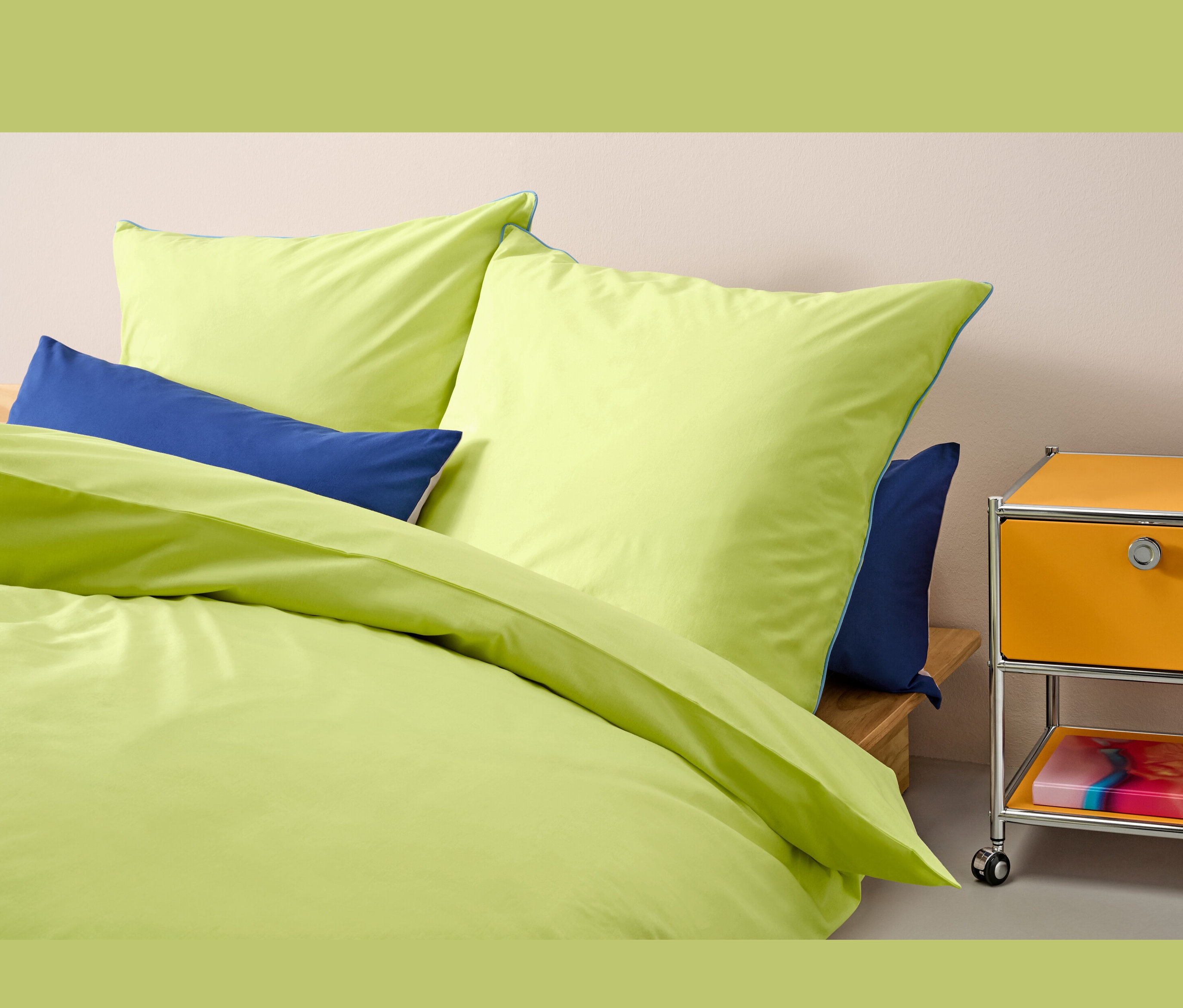 Parure de lit en renforcé jaune taille normale sur un lit avec des oreillers bleus.