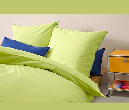 Parure de lit en renforcé jaune taille normale sur un lit avec des oreillers bleus.