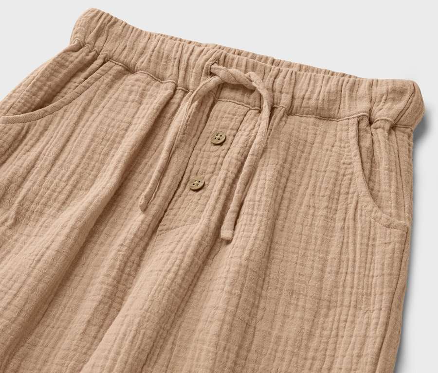 Gros plan d'un pantalon en mousseline pour enfant avec cordon de serrage et boutons.