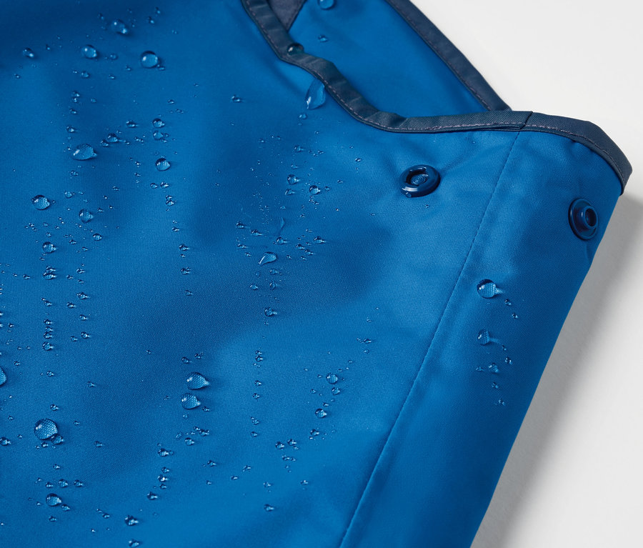 Gros plan sur un pantalon de pluie thermique bleu pour enfant avec des gouttes d'eau.