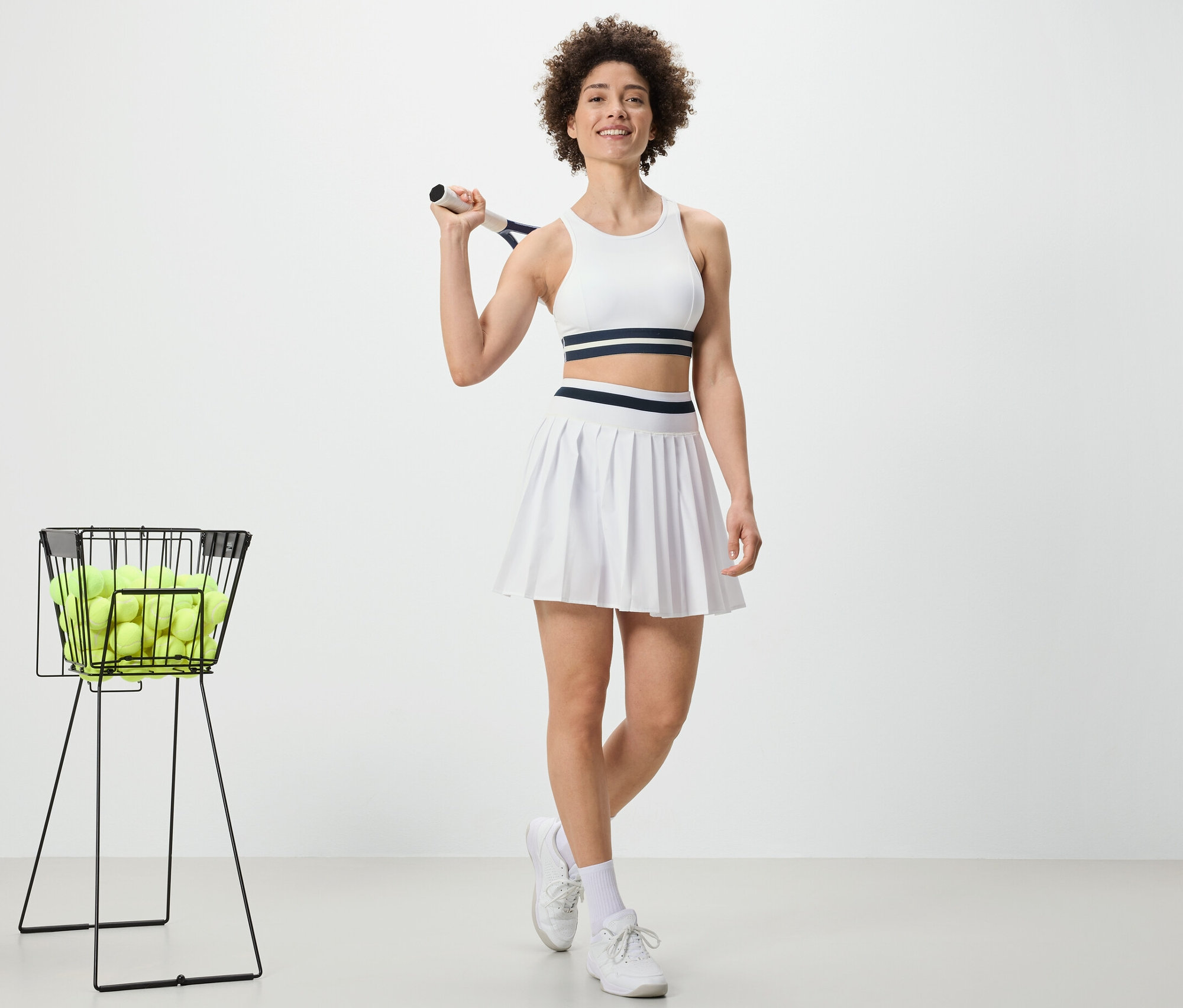 Femme tenant une raquette de tennis et portant une jupe de sport.