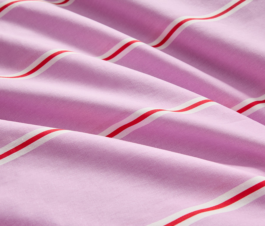 Gros plan d'un tissu rose rayé plié avec des rayures rouges et blanches.
