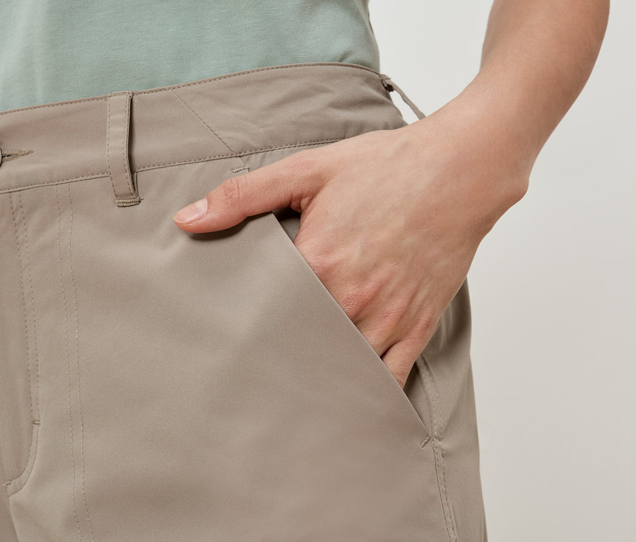 Une personne avec la main dans la poche d'un pantalon beige.