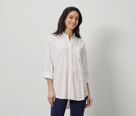 Femme portant une chemise en lin blanche et un pantalon bleu marine.