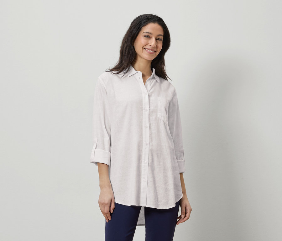 Femme portant une chemise en lin blanche et un pantalon bleu marine.