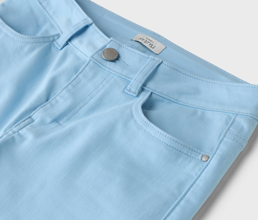 Gros plan sur un pantalon bleu clair avec bouton et poche.