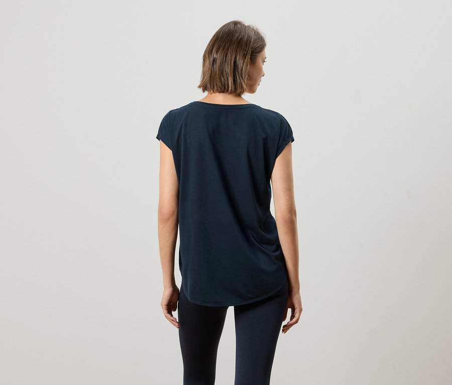 Vue arrière d'une femme aux cheveux bruns courts portant un t-shirt bleu marine et un legging.