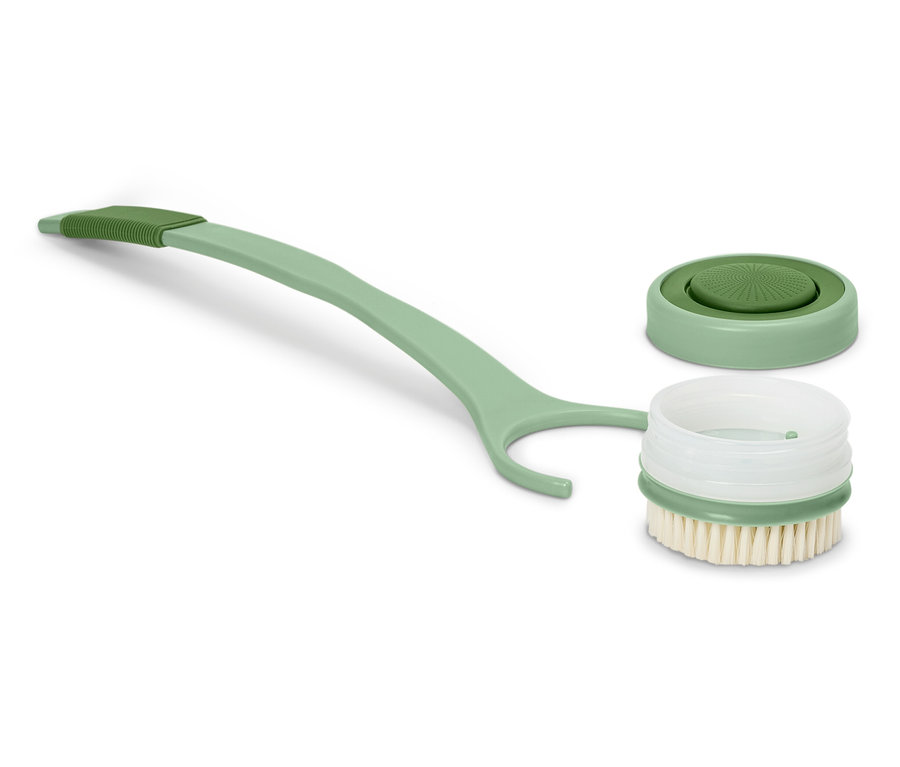 Une brosse verte à long manche est posée à côté d'un couvercle retiré.