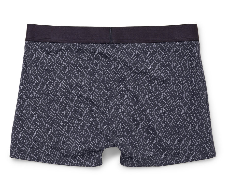 Gros plan d'un caleçon boxer avec un motif bleu et une ceinture foncée, posé sur un fond blanc.