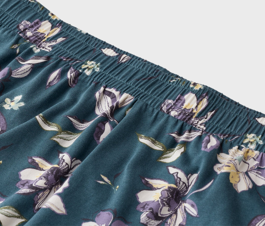 Gros plan d'un pantalon de pyjama bleu avec une taille élastique et un motif floral.