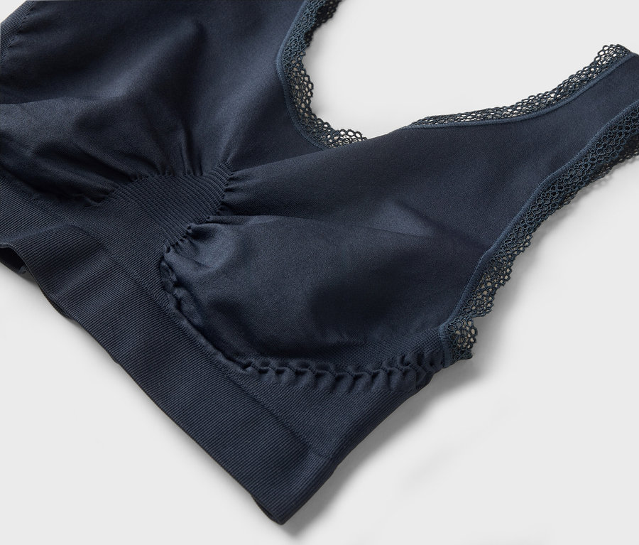 Gros plan d'un soutien-gorge bleu marine avec des détails en dentelle sur un fond gris.