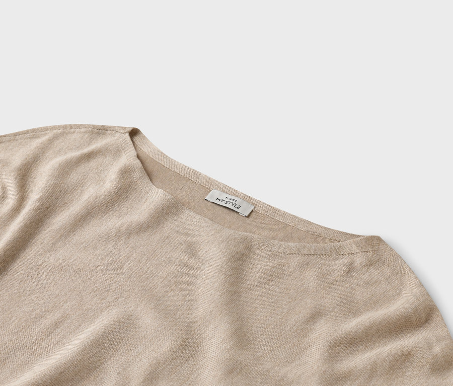 Gros plan d'un haut beige avec une étiquette 'TCHIBO MY STYLE'.