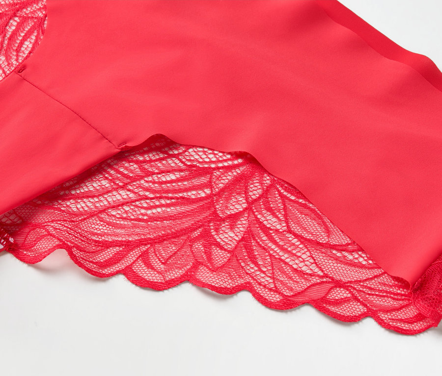 Gros plan d'un haut rouge pour femme avec des finitions en dentelle sur les manches et l'ourlet, sur un fond blanc.