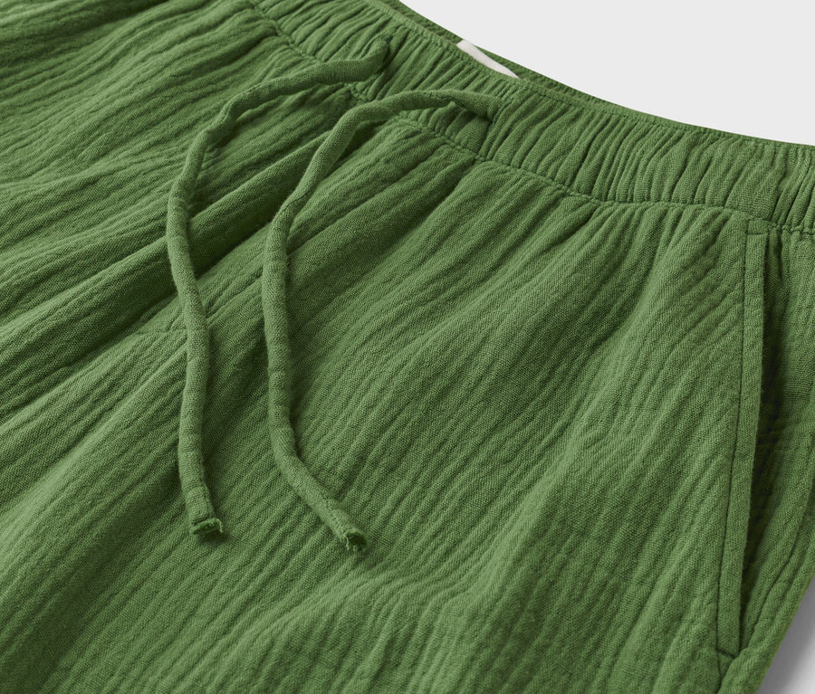 Gros plan d'un pantalon vert texturé avec cordon de serrage et taille élastique.