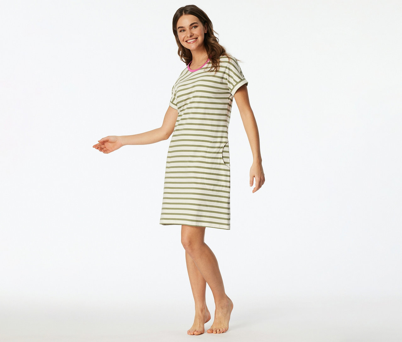 Femme souriante portant une chemise de nuit SCHIESSER courte à manches courtes, rayée vert olive et beige, avec un col rose et une poche, debout pieds nus.