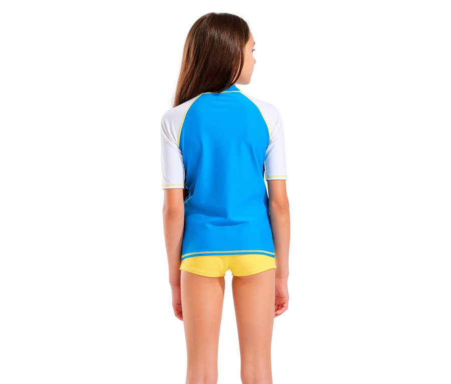 Vue de dos d'une jeune fille aux cheveux bruns portant un rashguard bleu et blanc et un short jaune.