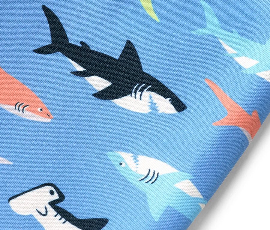 Tissu bleu avec motif de requins en noir, orange et bleu.