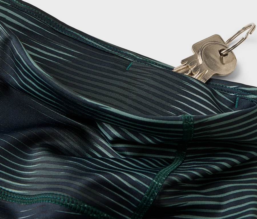 Des clés sont dans la poche d'un pantalon à motifs vert foncé.