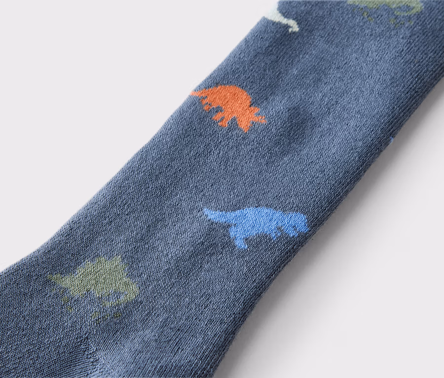 Gros plan d'une chaussette bleue avec des dinosaures orange, verts et bleus.