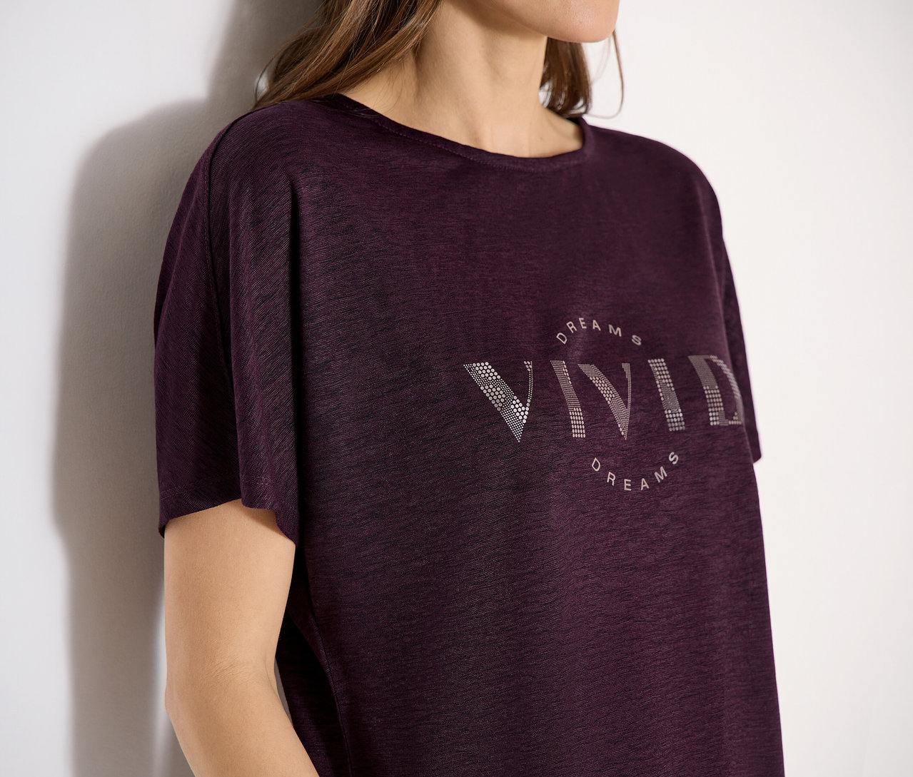 Une femme porte un t-shirt à manches courtes bordeaux CECIL avec l'inscription « VIVID DREAMS ».