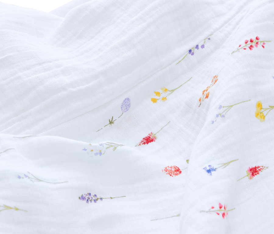 Gros plan d'un tissu en mousseline blanche avec de petits motifs floraux colorés.