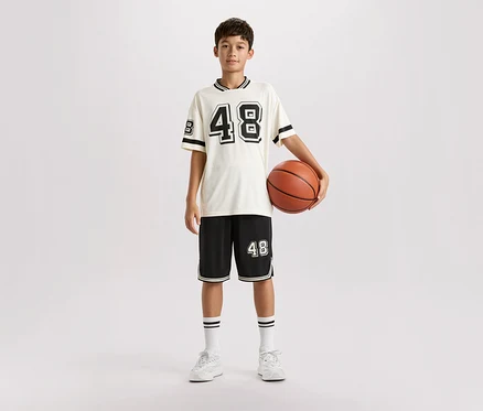 Un jeune homme se tient debout dans une tenue de sport et tient un ballon de basket.