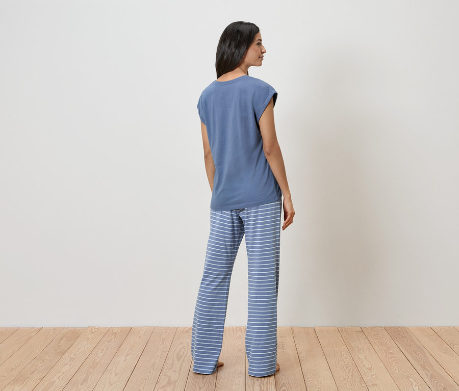 Femme de dos en t-shirt bleu et pantalon rayé.