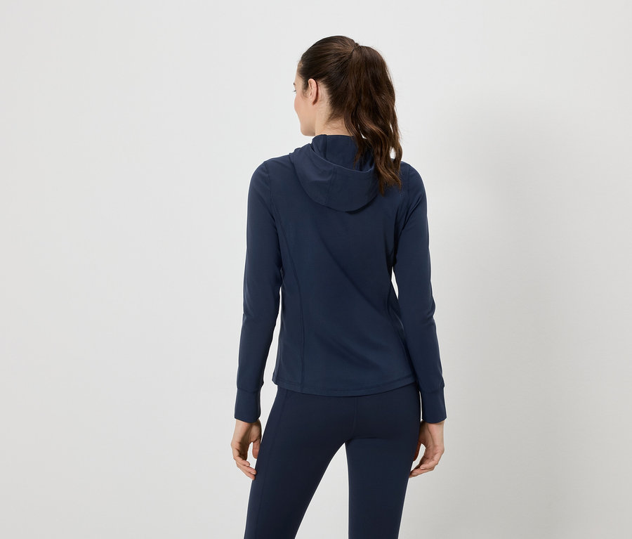 Vue arrière d'une femme portant un survêtement bleu marine avec une veste à capuche et un legging, les cheveux attachés en queue de cheval.