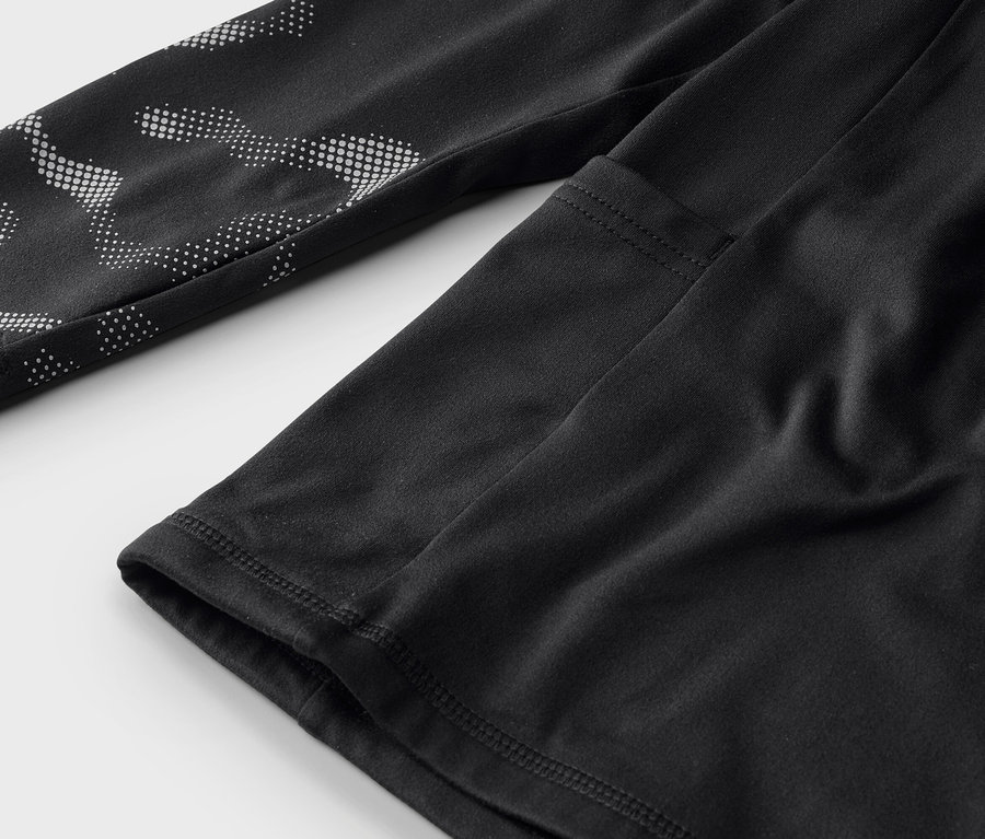Gros plan d'un haut de sport noir à manches longues avec des motifs à pois blancs sur la manche.