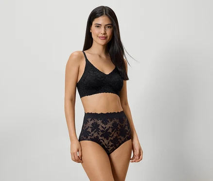 Femme portant un soutien-gorge en dentelle noire et une culotte taille haute sur fond clair.