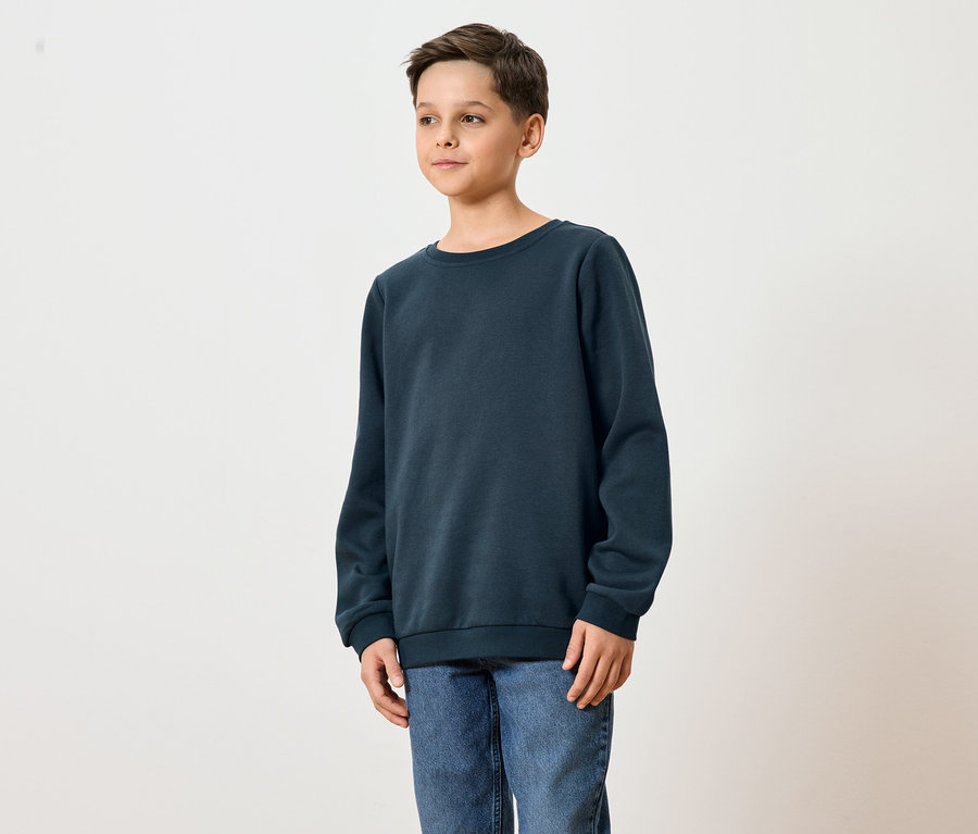 Un jeune homme porte un sweat-shirt bleu marine et un jean.