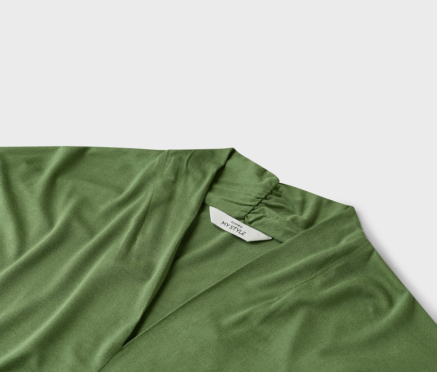 Gros plan d'un haut cache-cœur vert avec un col en V et une étiquette indiquant « TCHIRO MY STYLE ».