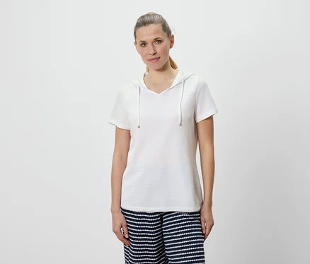 Femme portant un t-shirt blanc à capuche et un pantalon rayé bleu et blanc.