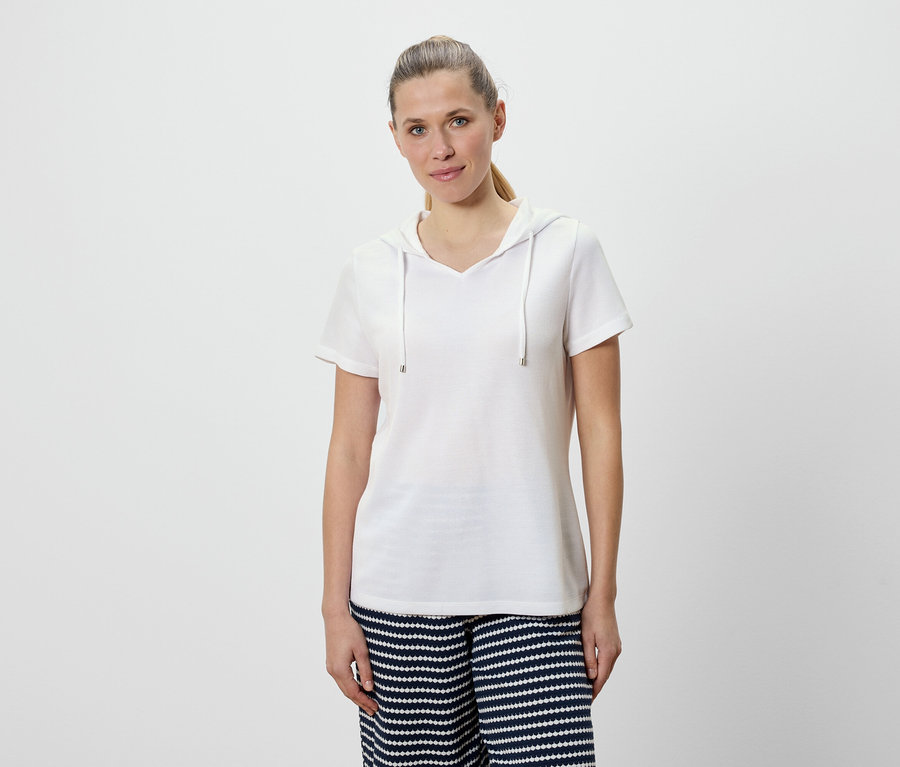 Femme portant un t-shirt blanc à capuche et un pantalon rayé bleu et blanc.