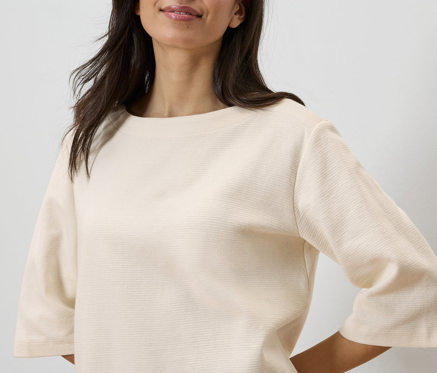 Gros plan d'une femme portant un haut texturé de couleur claire.