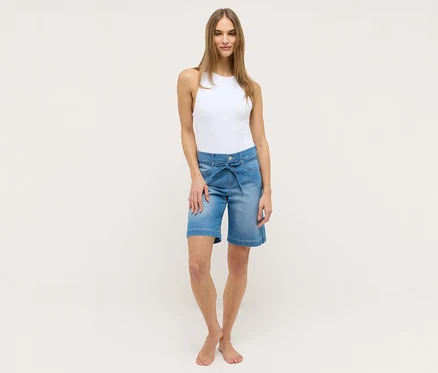 Femme portant un débardeur blanc et un short Angels Denim «
Lia City
», bleu clair, avec ceinture à nouer.