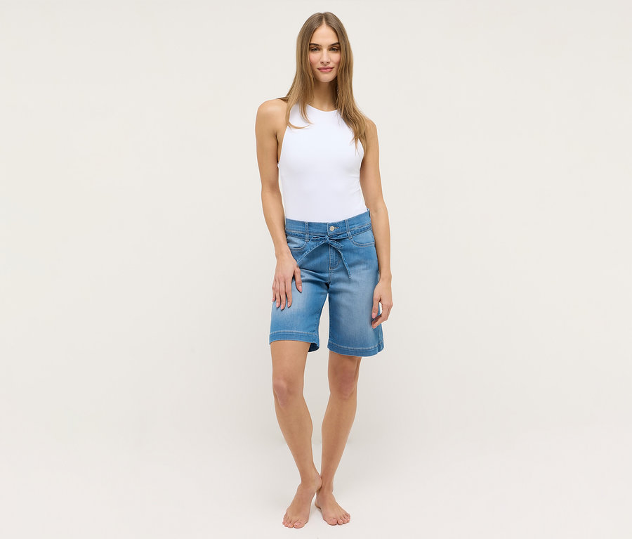 Femme portant un débardeur blanc et un short Angels Denim «
Lia City
», bleu clair, avec ceinture à nouer.
