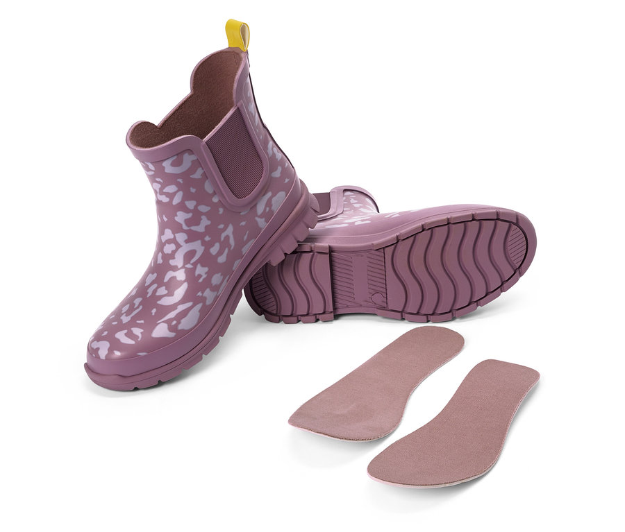 Deux bottes en caoutchouc violettes à motif blanc et languette jaune, à côté de deux semelles intérieures.