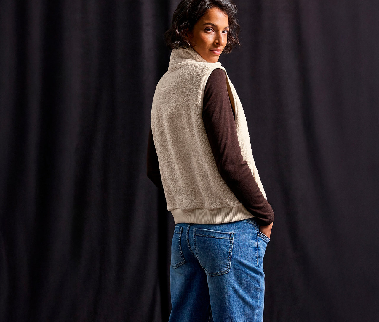 Femme portant un haut marron et un jean bleu, avec une veste en teddy Street One, regardant par-dessus son épaule.