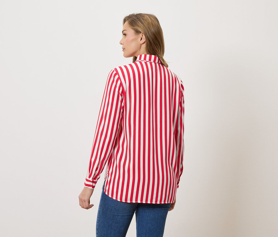 Femme vue de dos portant un chemisier rayé rouge et blanc et un jean.