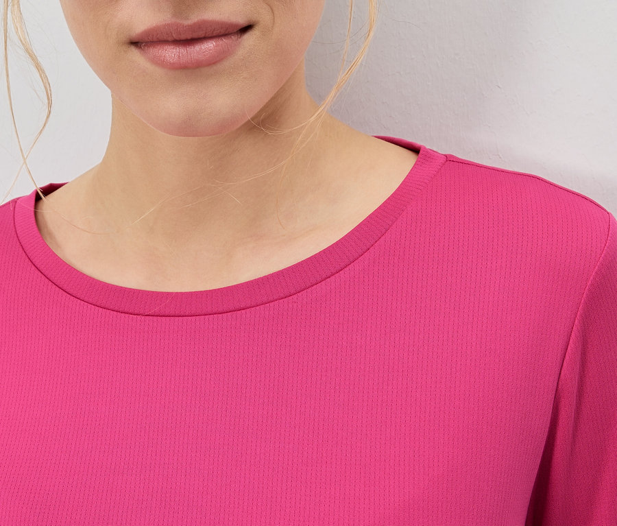 Gros plan d'une femme portant un haut rose.