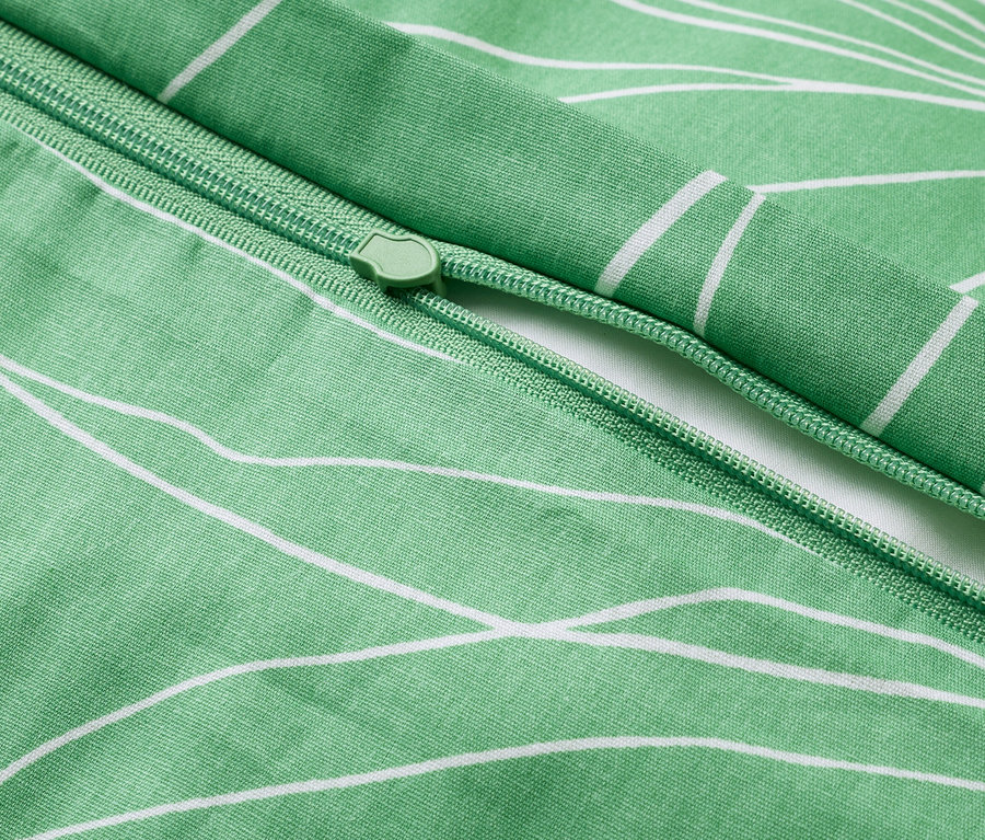 Gros plan d'une housse de couette verte à motif floral blanc avec fermeture éclair.