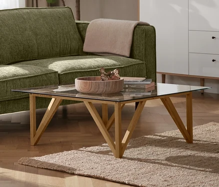 Un canapé 3 places en velours côtelé vert dans un salon, à côté d'une lampe de table en métal noire et d'un meuble haut « Bekeson » blanc.